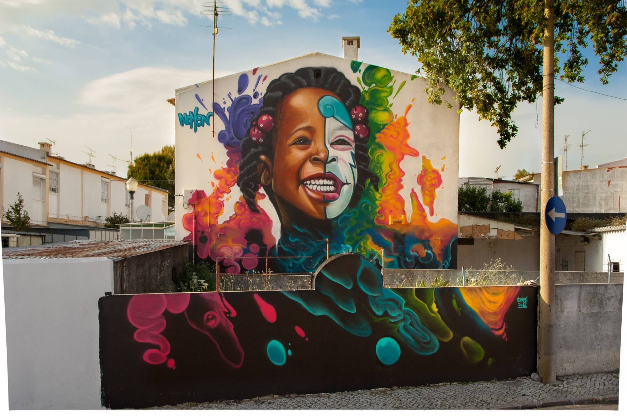 A vibrant mural of a smiling child with colorful splashes and graffiti elements