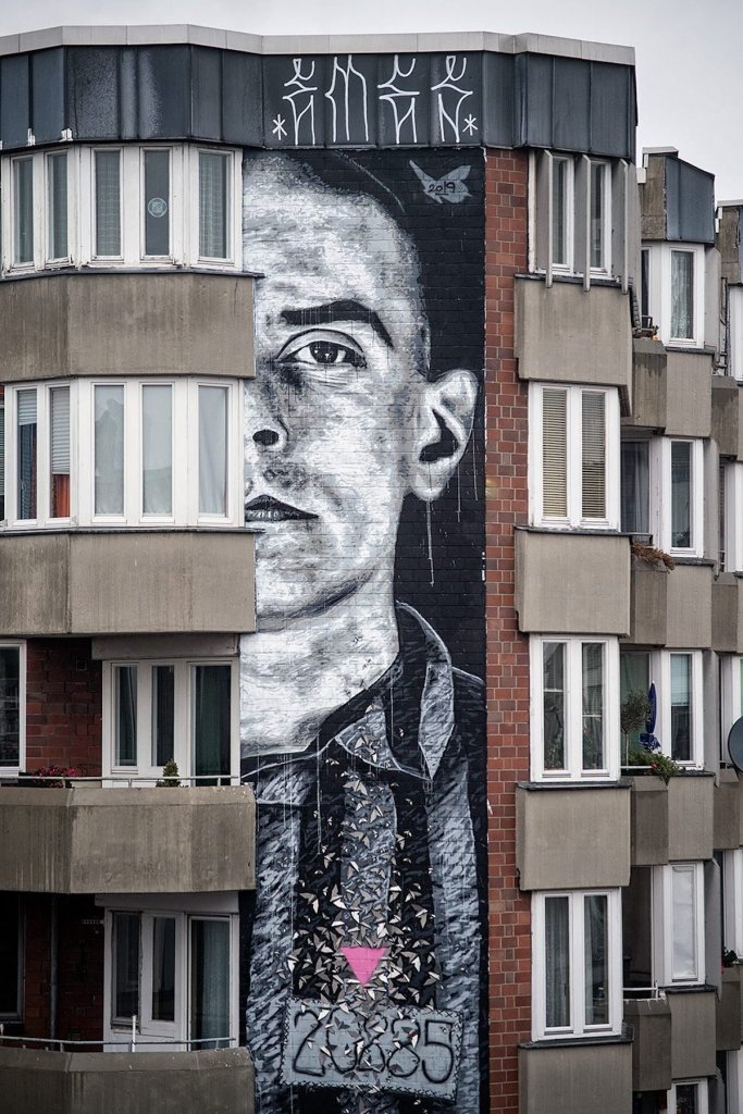 The memorial wall portrait by Nils Westergard shows the Auschwitz detainee Walter Degen in his concentration camp prisoner’s uniform and with his prisoner number 20285, as well as the pink triangle on his left breast. Berlin 2019. Photo Credit Nika Kramer / Urban Nation